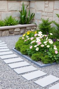 Image Prompt: A wide garden bed edged with smooth, curved concrete, soft-colored flowers inside, and grass on the other side.