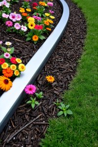 Image Prompt: A garden border lined with upright curved terracotta tiles, forming a charming orange-red edge against green plants and brown soil.