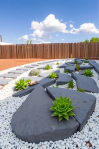 Image Prompt: Front yard rock garden with large flat stones, small white pebbles, and green succulents spaced in a modern design.
