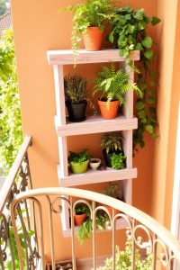 Image Prompt: Cozy garden nook on balcony with a small chair, hanging lights, and plants on all sides.